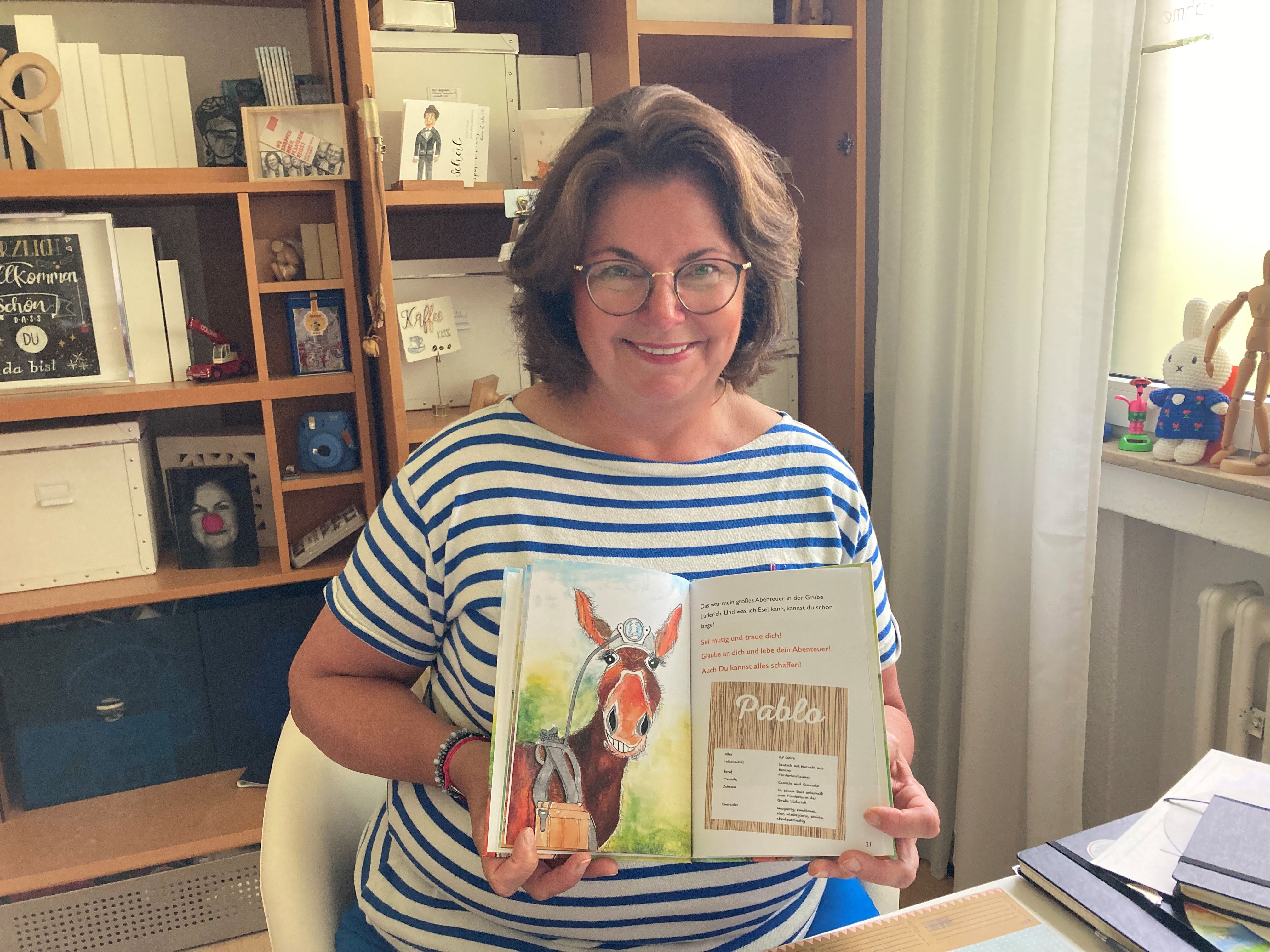 Die Illustratorin Sabine Di Martino präsentiert stolz den Esel in „Pablos größtes Abenteuer“ von Sabina Henrich. Foto: Anne Siebertz